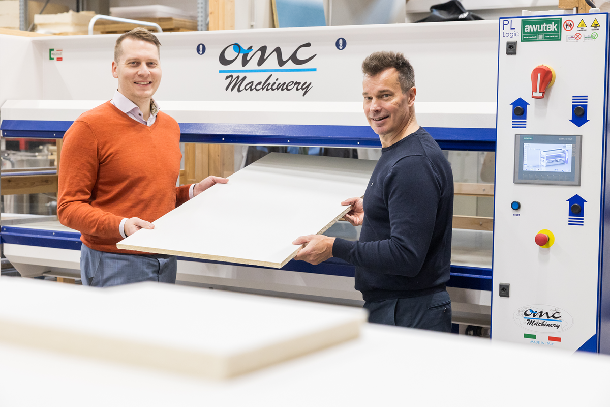 Toimitusjohtaja Mikko Paananen (vas.) ja teknologiajohtaja Petri Jetsu puristimen äärellä käsissään valmis ja pinnoitettu Aistin akustiikkalevy.