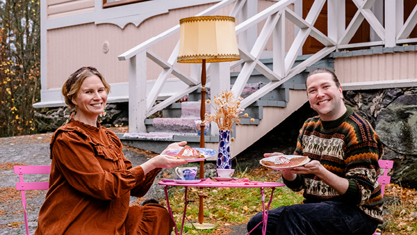 Nainen ja mies syövät lettuja puisen huvilarakennuksen edessä.