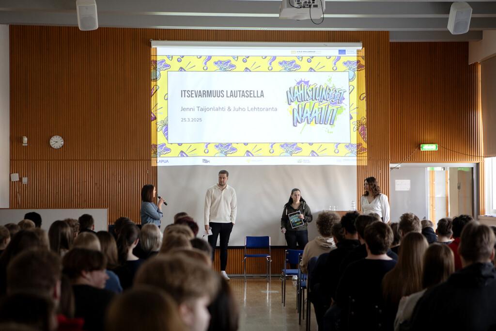 Ihmisiä puhumassa yleisön edessä. Taustalla teksti "Itsevarmuus lautasella - Jenni Taijonlahti & Juho LEhtoranta 25.3.2+25 - Nahistuneet naatit.