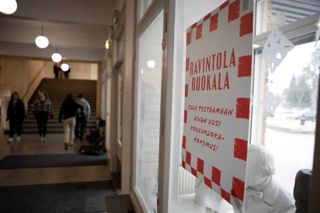 Juliste koulun seinällä: "Ravintola ruokala - Tule testaamaan aivan uusi kouluruokakokemus!".